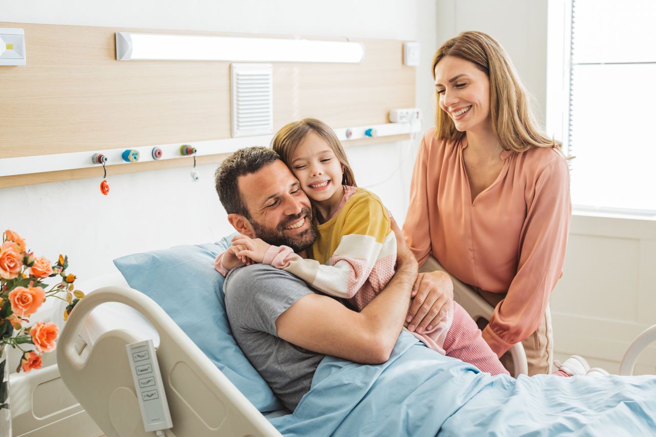 Eine Familie sitzt auf einem Sofa und schaut ein Fußballspiel an.